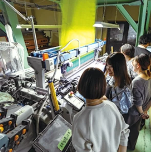 織物工場で織機を見学する人々