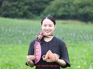 畑でサツマイモを抱える女性