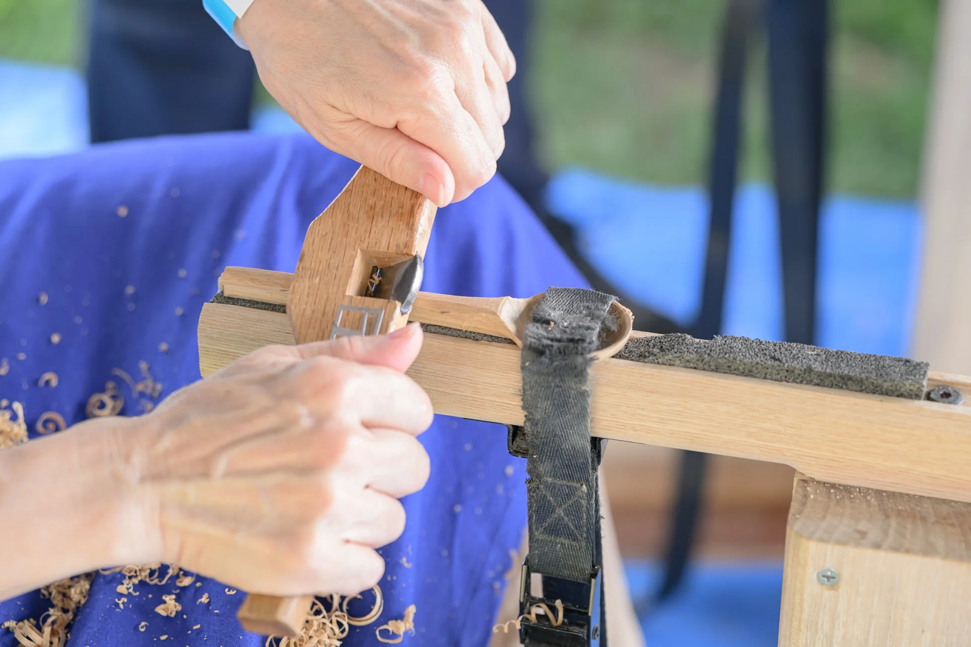 木材加工をする人の手が写っており、木片を削る作業の様子