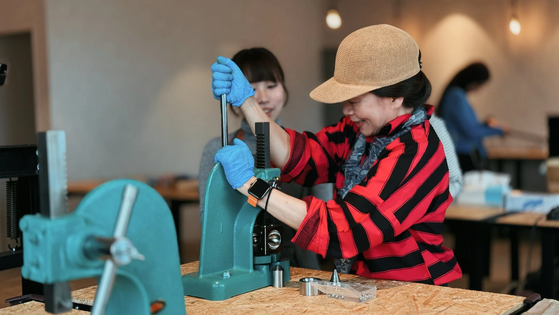 麦わら帽子をかぶった女性がプレス機を操作している様子
